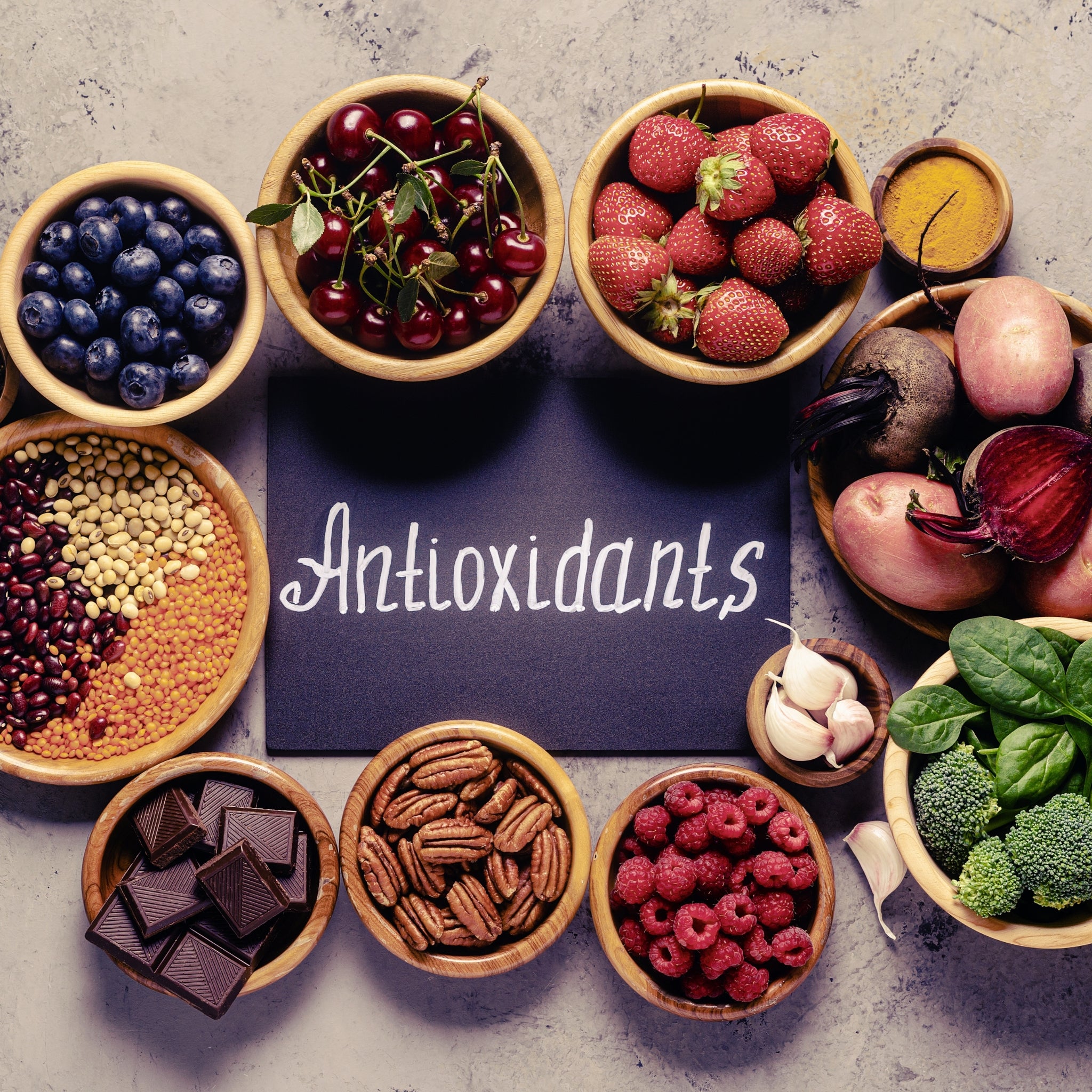 An assortment of antioxidant-rich foods, including berries, leafy greens, beans, and dark chocolate