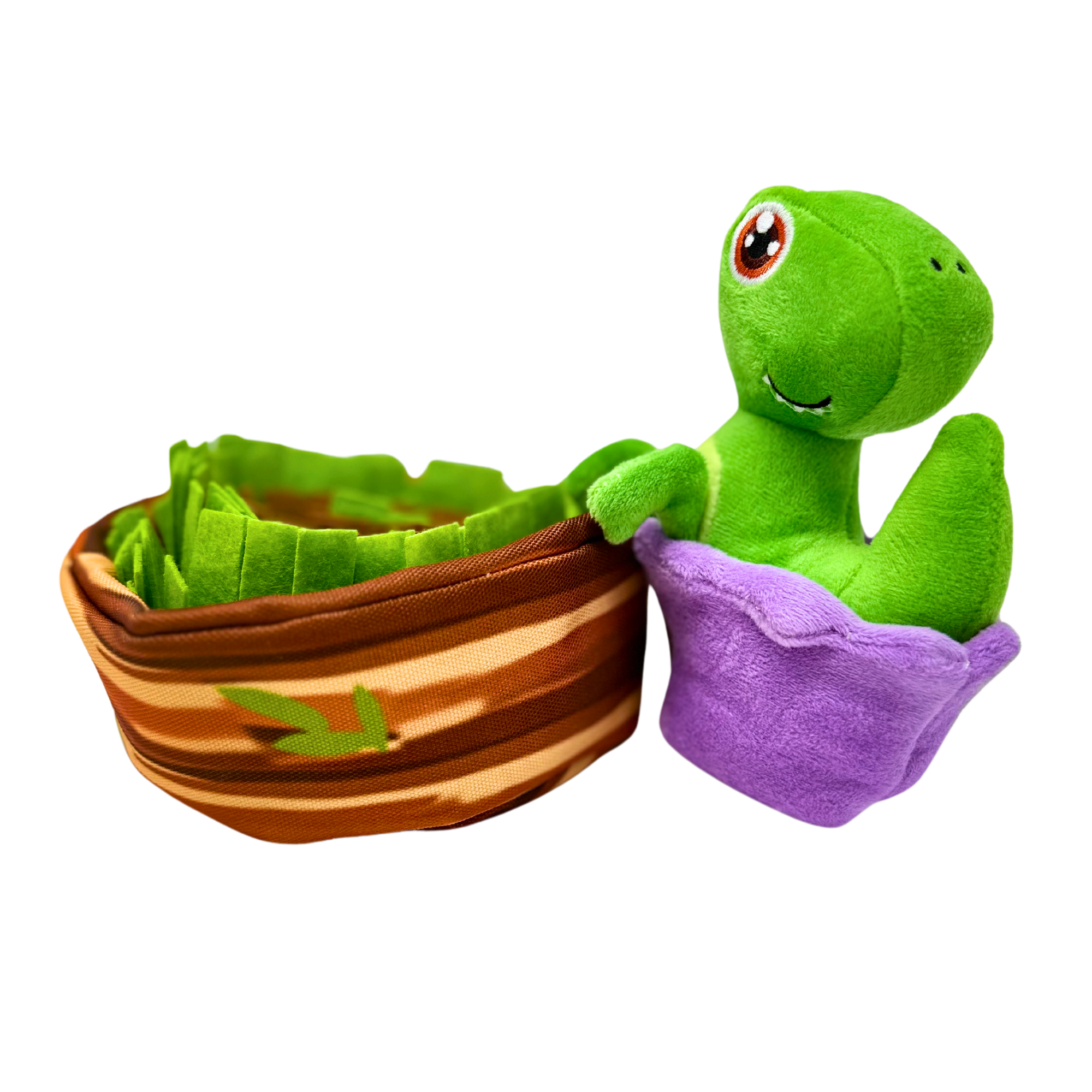 Plush green dinosaur with large eyes in a purple egg-like pod beside a round nest of layered green and brown fleece flaps