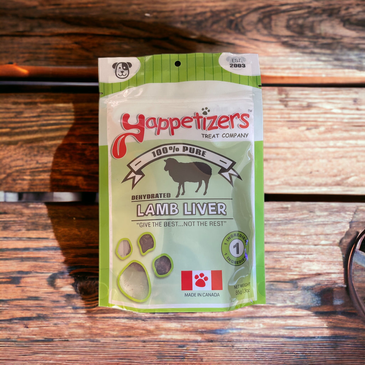 An 85g/3oz bag of natural dehydrated lamb liver made in Canada by Yappetizers. The treat bag is on a wooden bench.