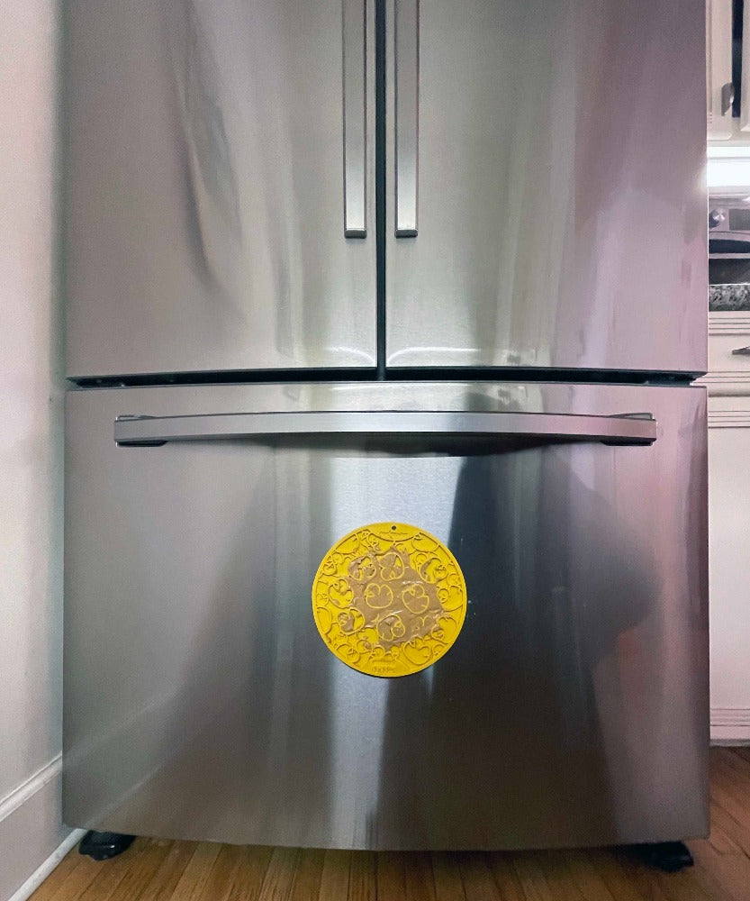 Yellow Duckies lick mat stuck to a fridge door with its suction cups