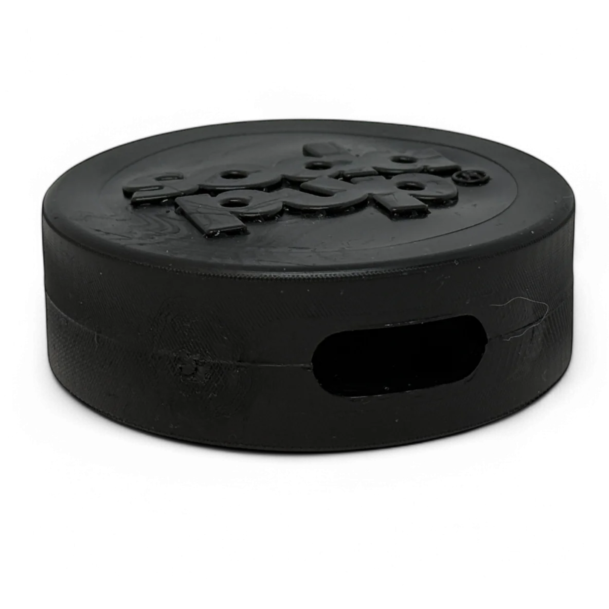 Close-up of a black rubber hockey puck-shaped with embossed "soda pup" logo and treat slot