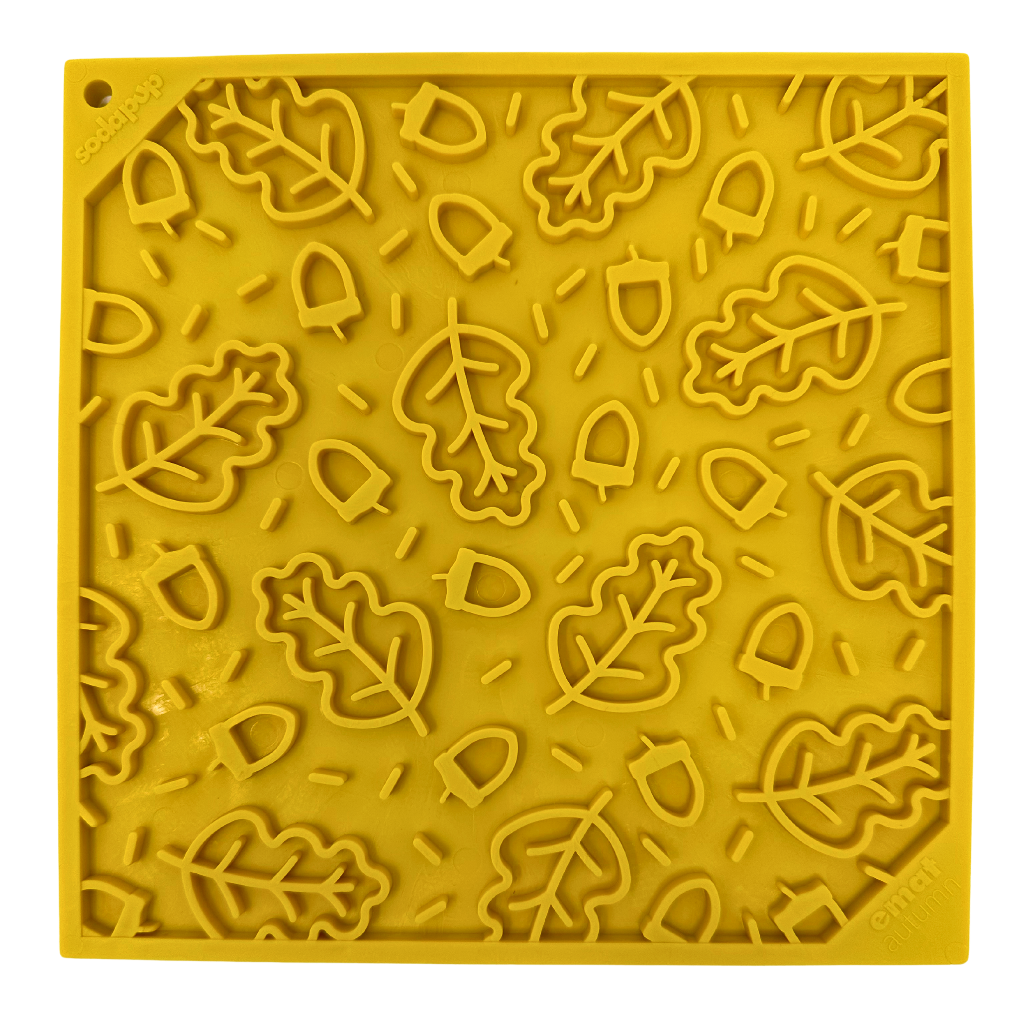 Close-up of a yellow dog lick mat with a textured leaf and acorn design